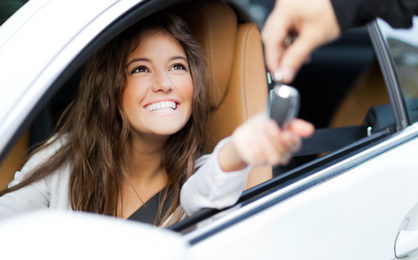 woman-receiving-keys-of-her-new-car-from-dealer